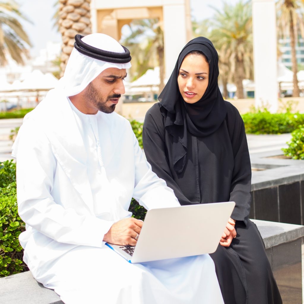 Arab couple in traditional clothes in the park with a laptop