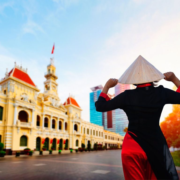 Vietnamese woman wearing traditional country attire in front of Ho Chi Minh city hall