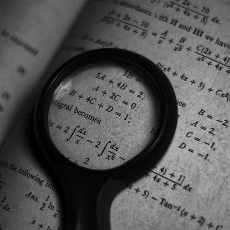 Magnifying glass on top of a book for French translators with specific numbers and formulas
