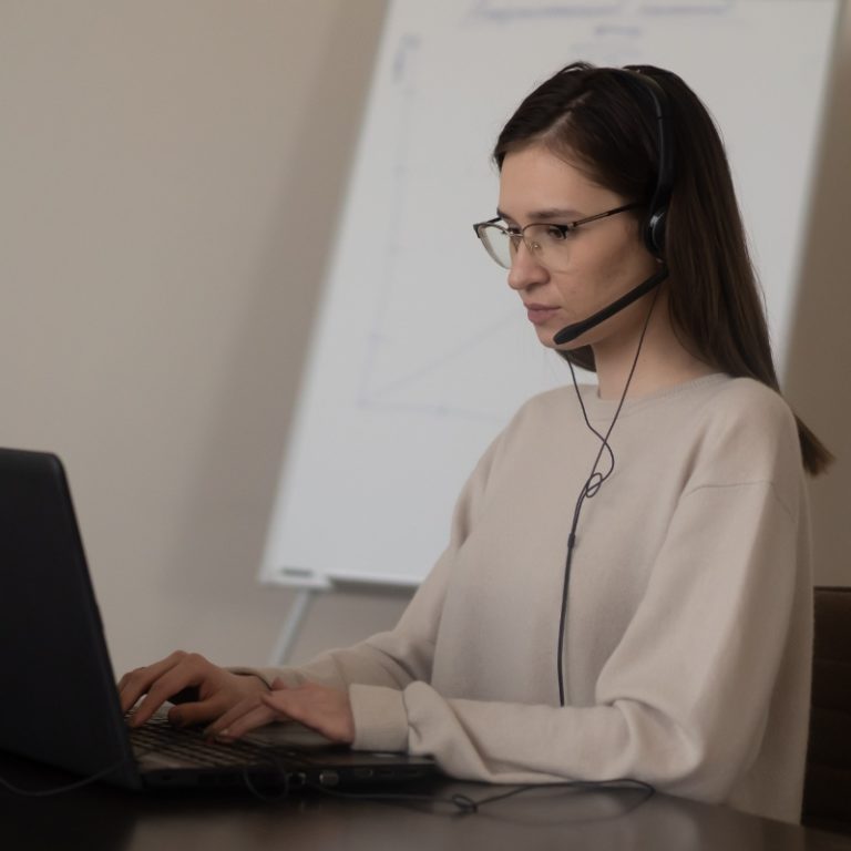 female english to french translator wearing a remote interpreting headset and using a laptop to communicate with clients