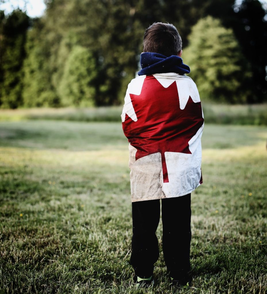 boy wearing sweatpants, hoodie and an old Canadian flag that was found at the bottom of Lake Huron