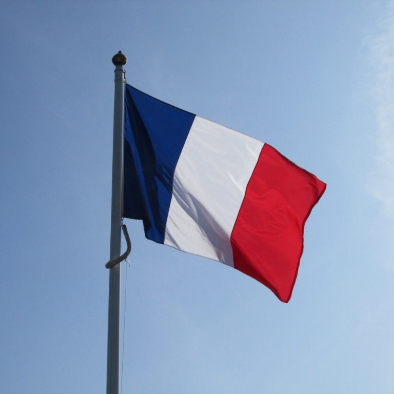 french flag on pole flying high against blue sky
