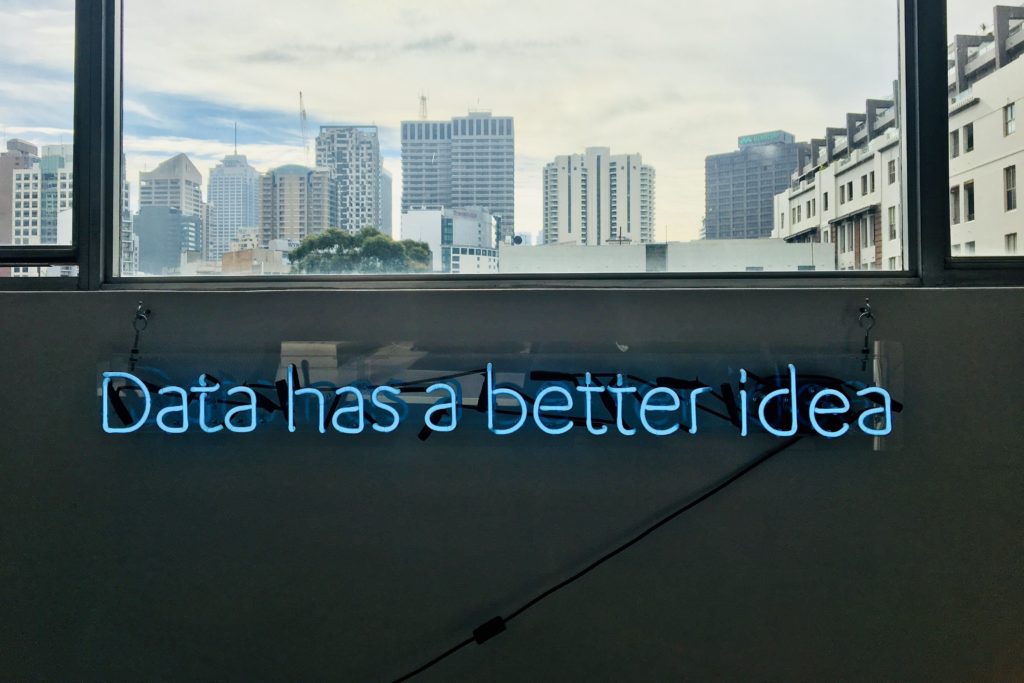 Neon light shaped into words Data Has a Better Idea with city skyline in the background