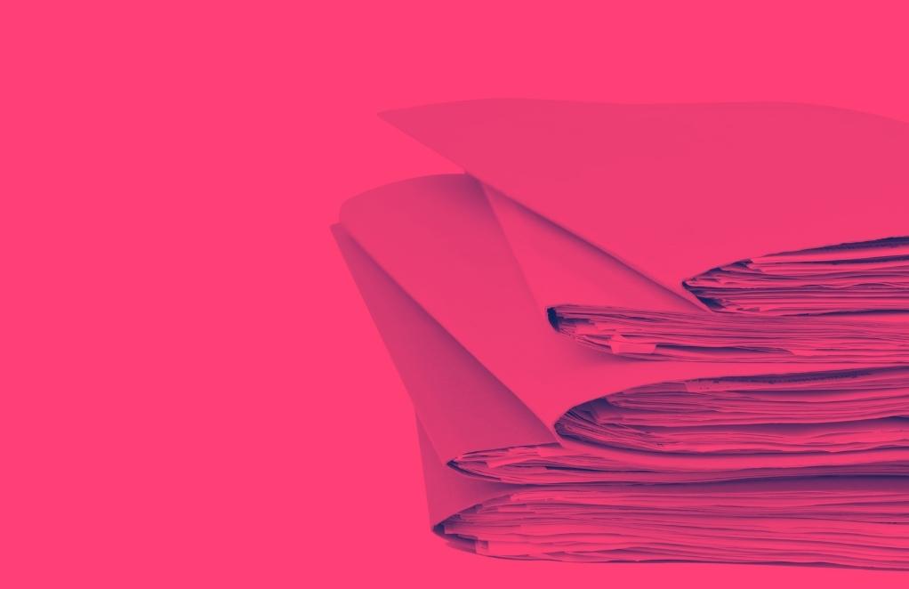 heap of documents in folders stack on each other against pink background