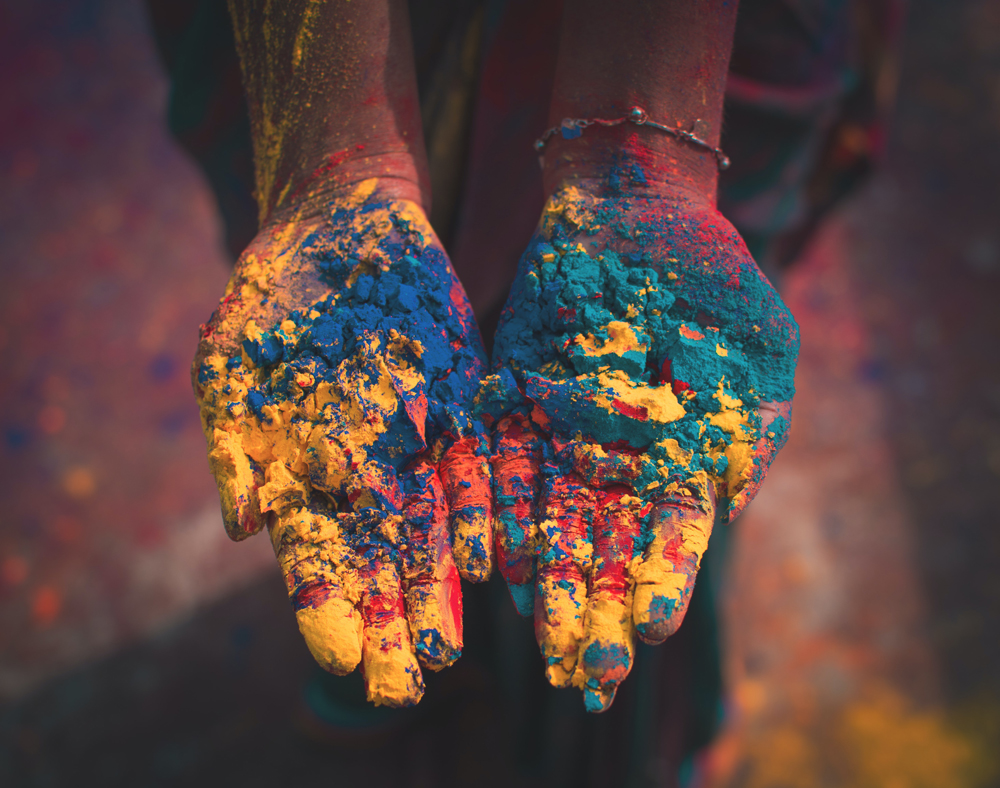 Woman's hands covered in yellow, blue, pink and green powder used during Diwali