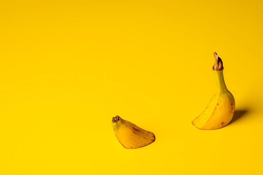 Yellow banana cut in half sinking in yellow background