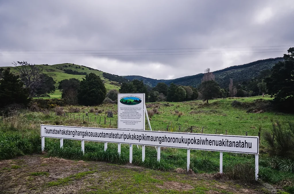 a very long name of a town on a road sign against green bushes in background
