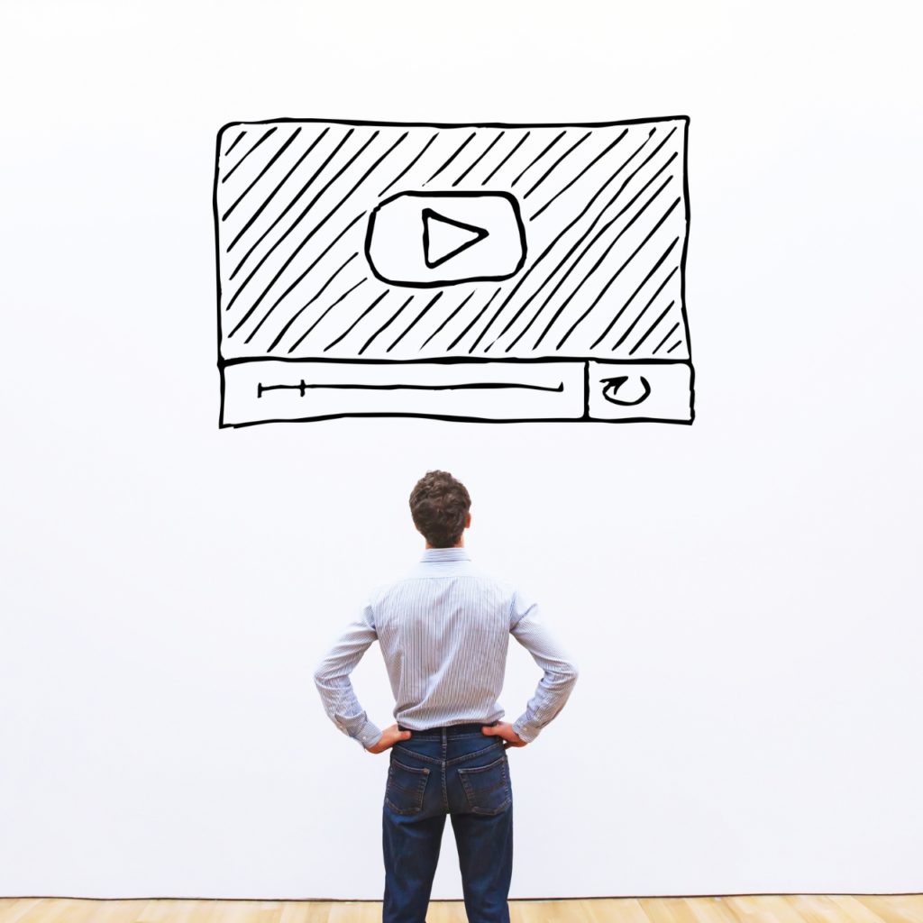 man looking at a drawn video marketing concept on white wall