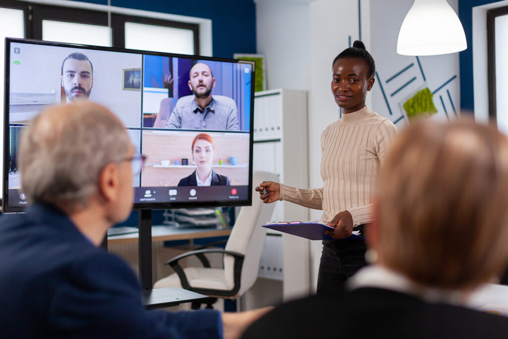 African woman discussing with remote managers on video call presenting new partners on webcam. Business people talk via webcam, do online conferences, participate in internet brainstorming, and distance office discussions.
